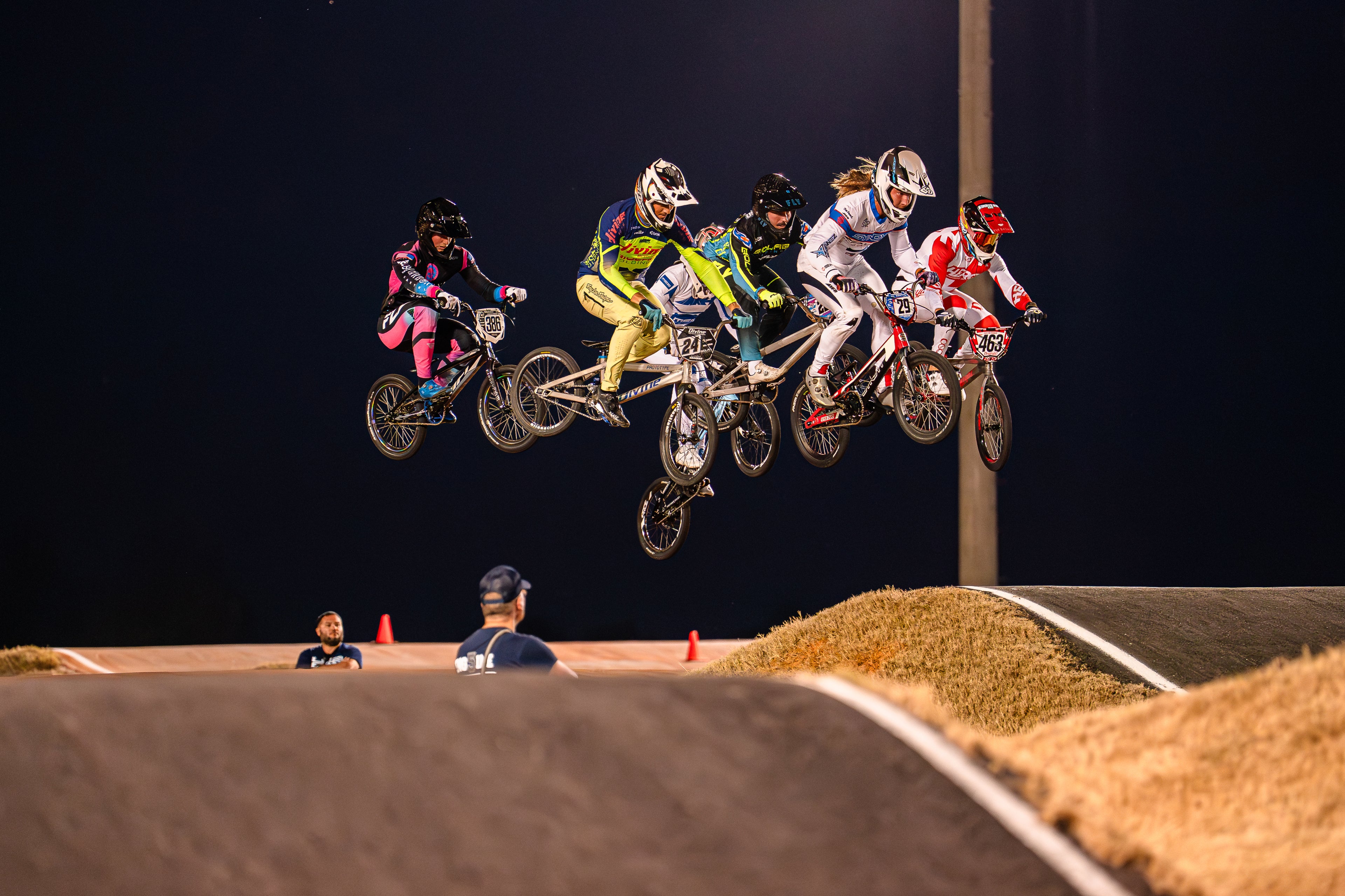 BMX racers in mid-air during a bicycle motocross event with dark sky background